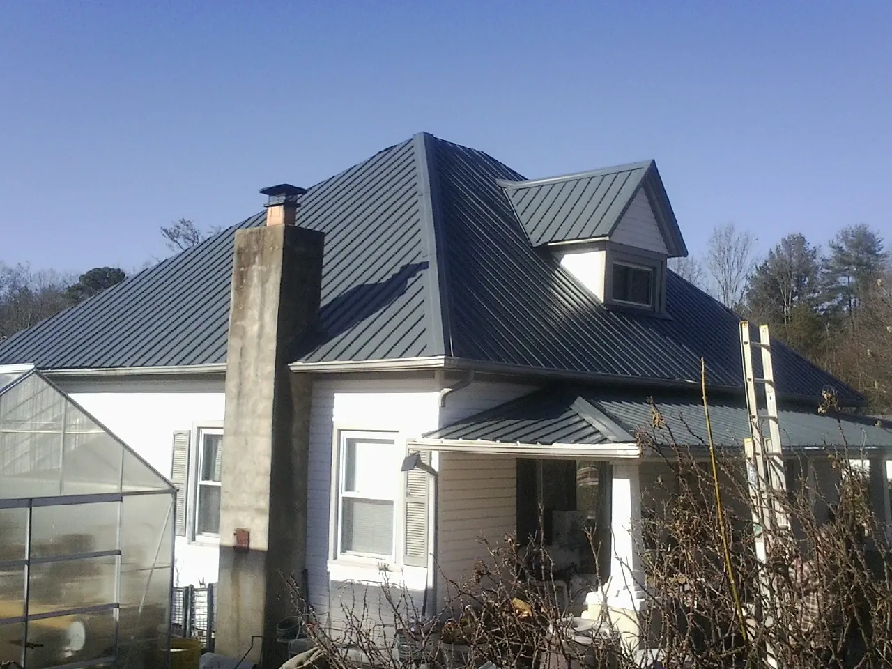 Dark blue standing seam metal roof on a white farmhouse with dormer — Slate & Tile Roof Repair by Roofing Brothers in Greeneville