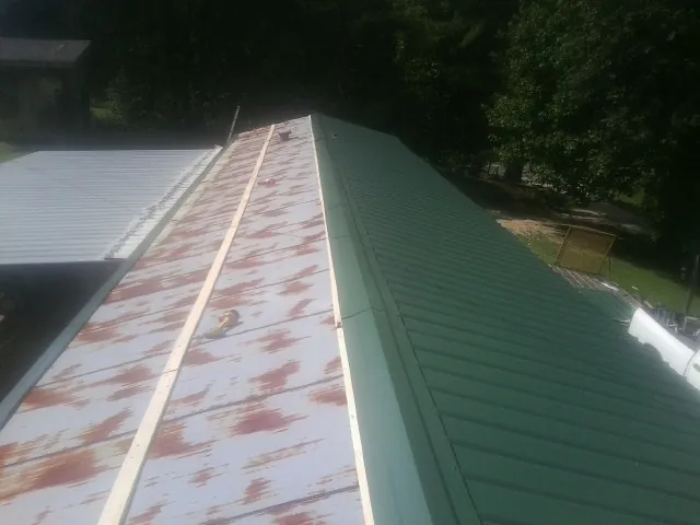 Old rusted panels beside newly installed green metal roofing — Wind Damage Roof Repair by Roofing Brothers in Greeneville