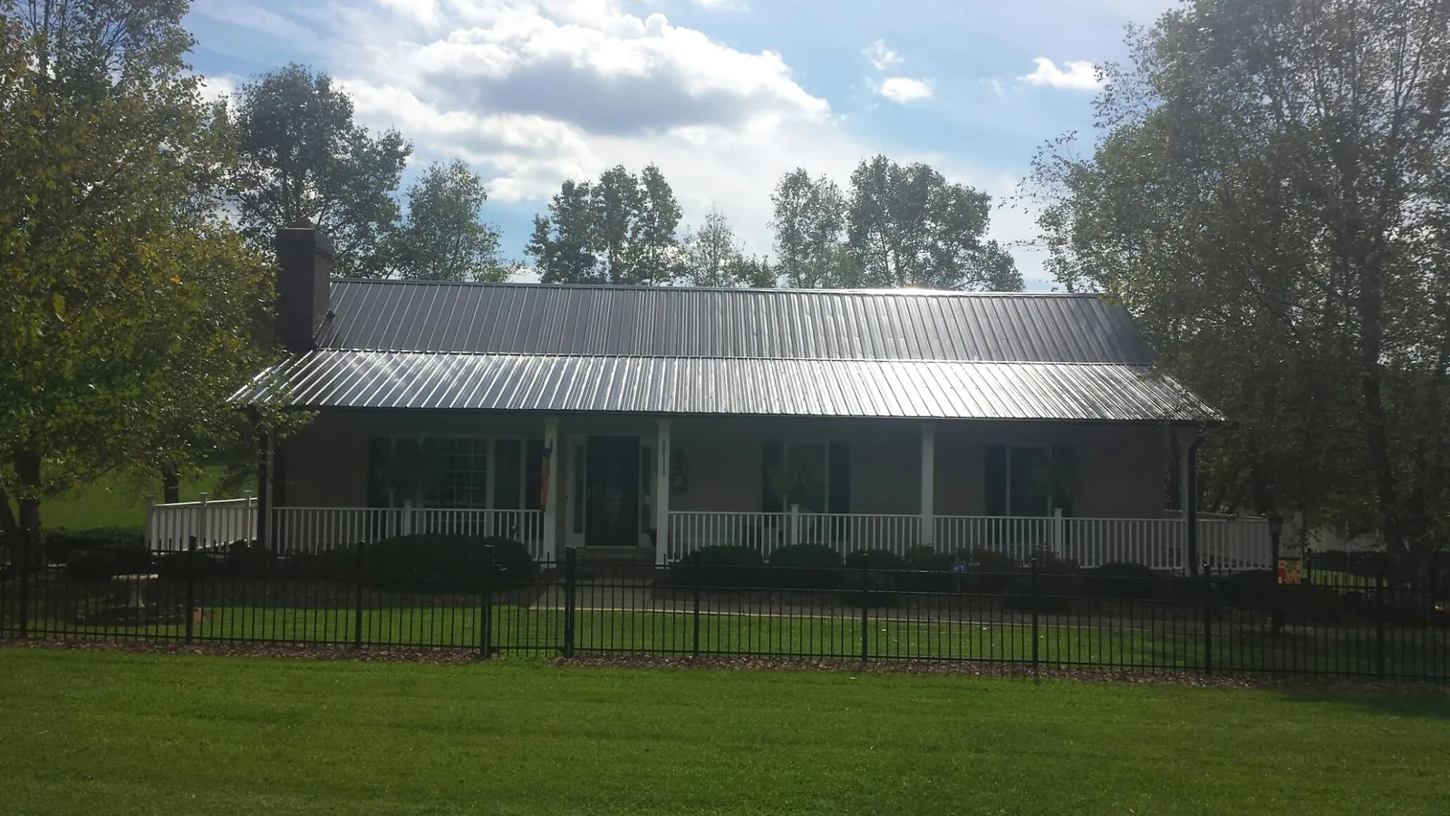 Gray metal roof on a brick ranch with a full width front porch — Gutter Guard Installation work by our crew in Greeneville