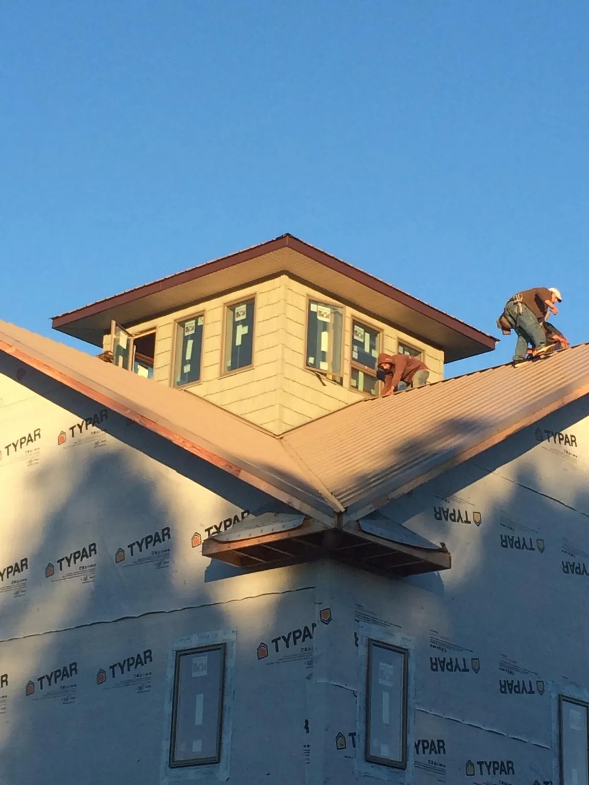 Roofers working around a rooftop cupola on a new metal roof at sunset — Roof Waterproofing in Greeneville by Roofing Brothers